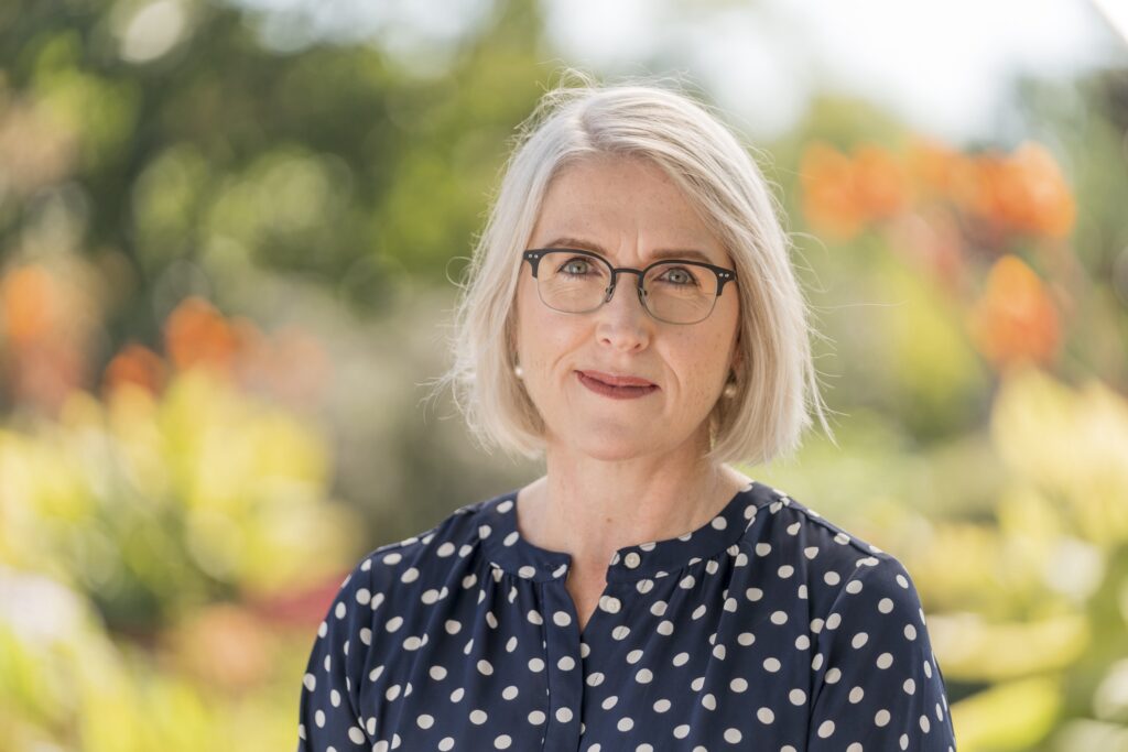 Portrait of Morven McLean taken outside with greenery behind her