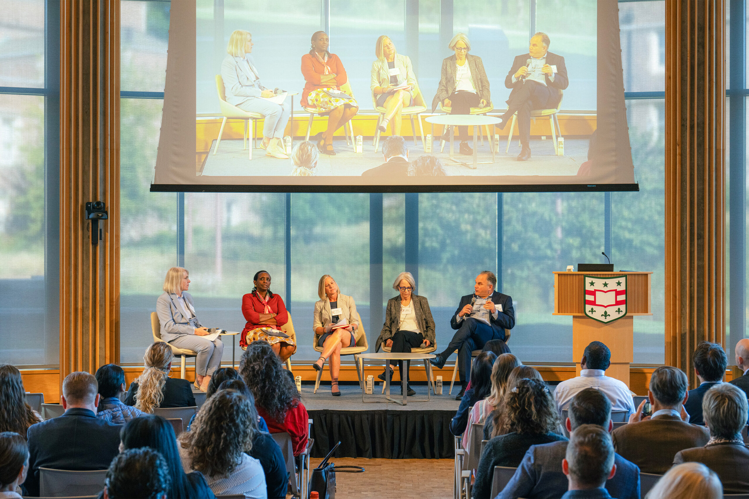 Panel presenters sit on a stage in front of an audience.