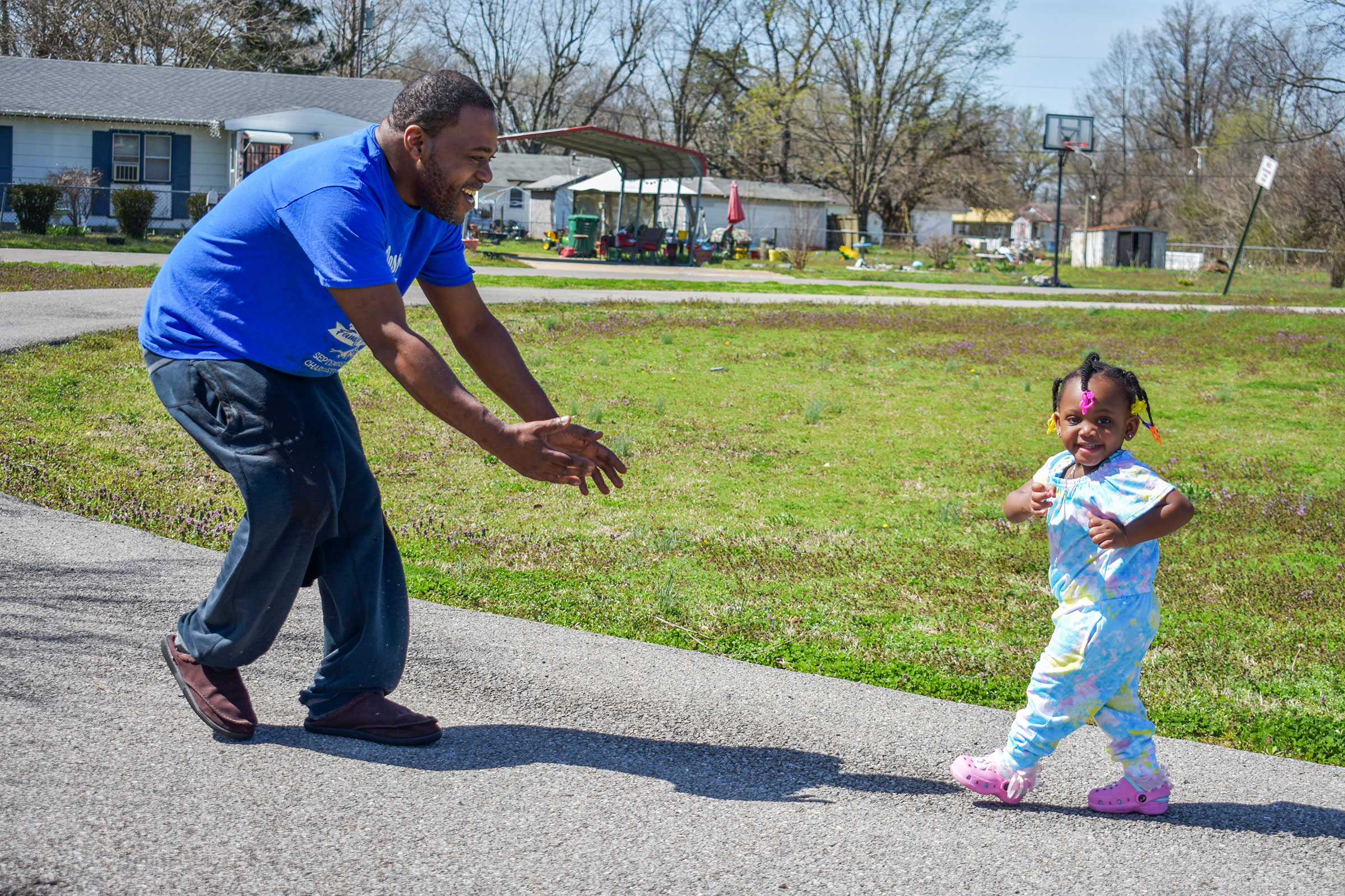 A man playing outdoors with his toddler daughter.