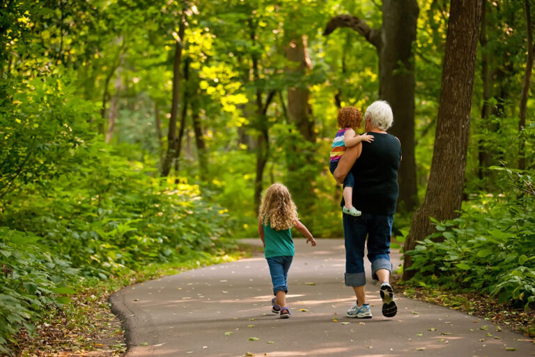 Grandmother and two young grandchildren walk on a trail