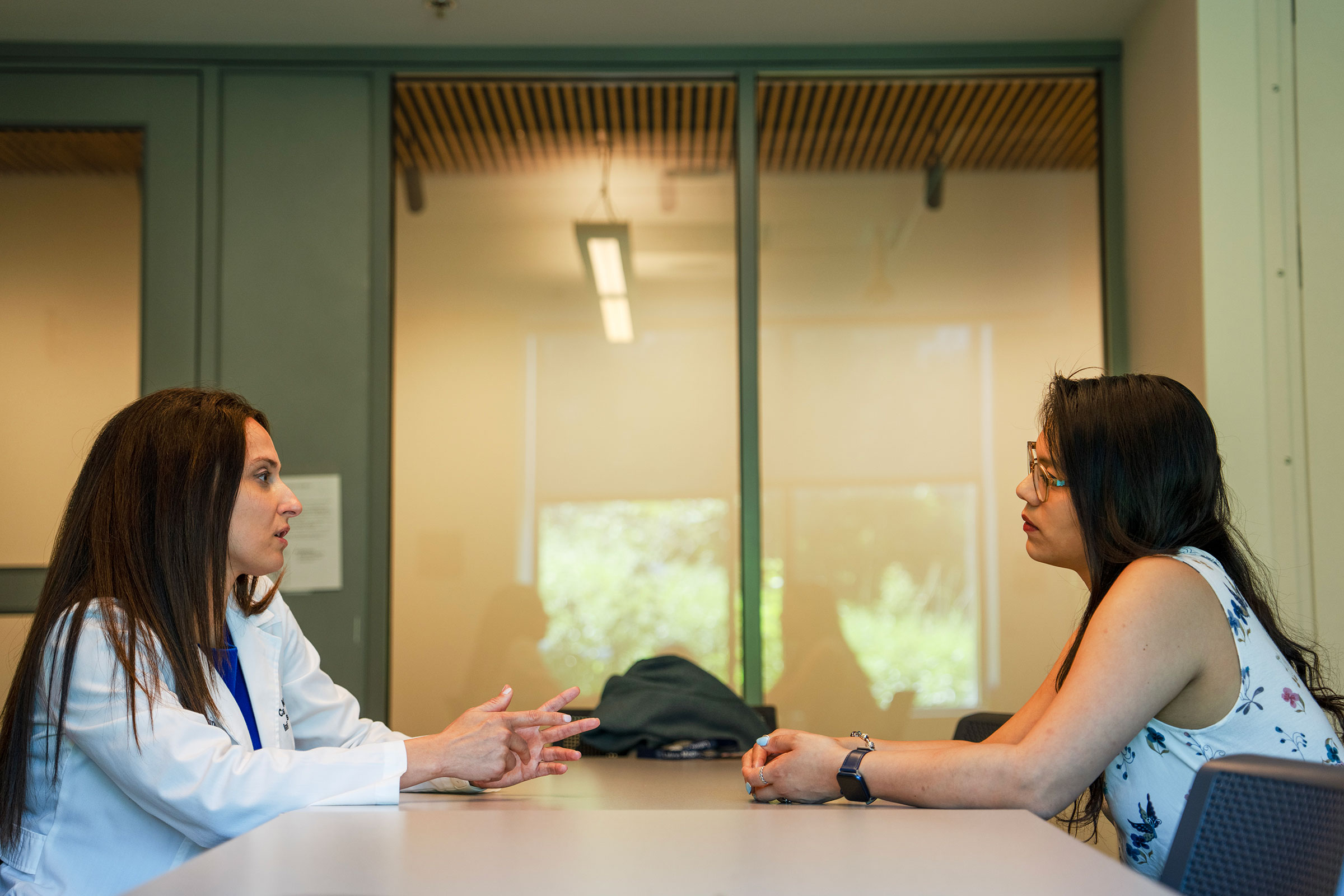 Two women talk over an office table