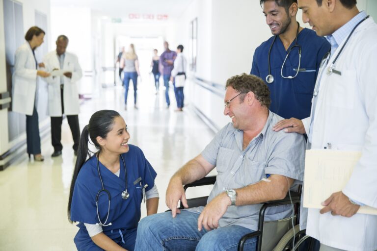 Getty -- doctors and nurse talking with pleased patient in a wheelchair. other health professionals in background