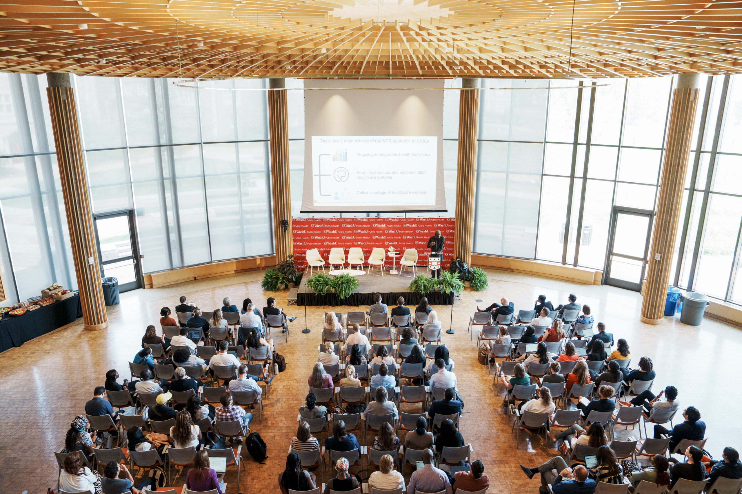 A filled lecture hall with a man speaking at the front.