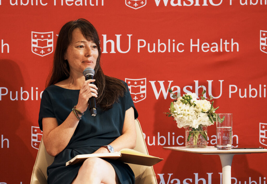 A woman holds a microphone while sitting on a stage