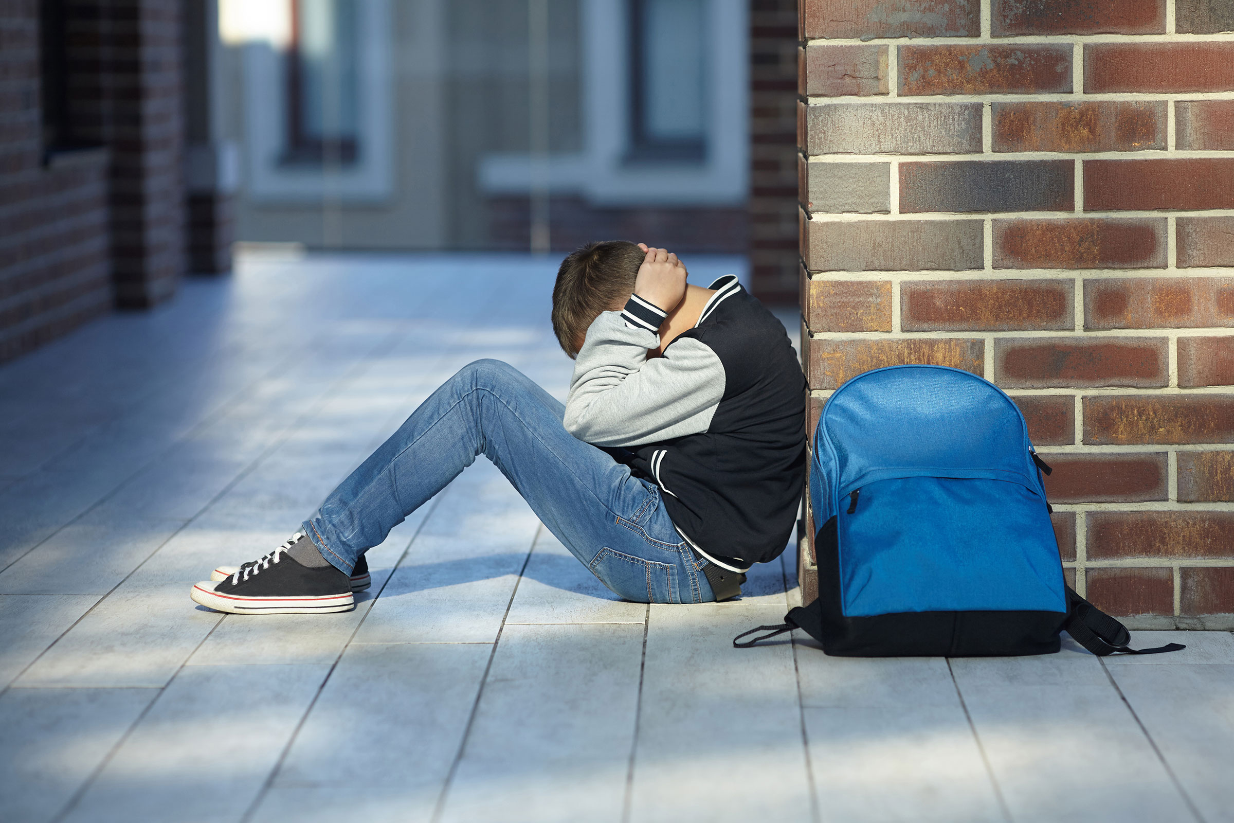 A boy sits on the ground looking sad