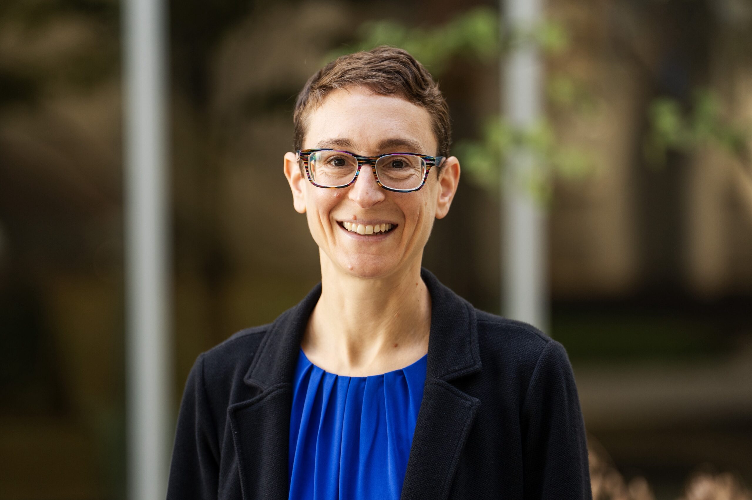 Rachel Tabak. woman with short, dark hair, glasses, blue shirt