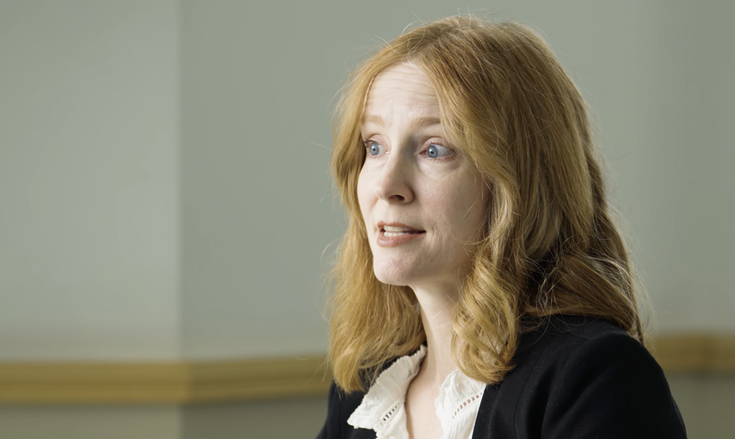 photo of woman with ginger/red hair smiling at the camera. She is a PhD student explaining her research.