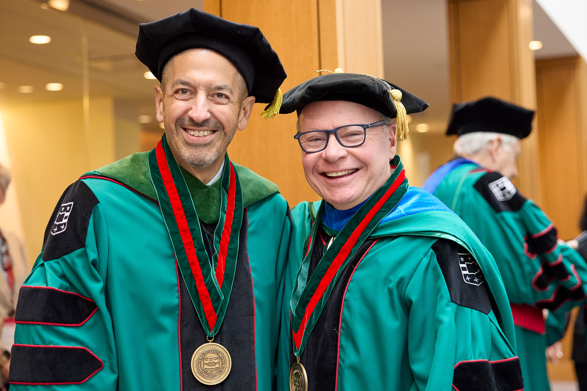 Sandro Galea and Andy Bursky stand in WashU graduation robes.